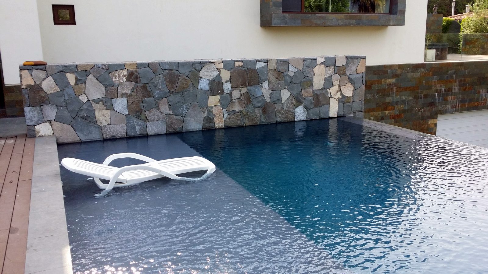 Piscina de borde infinito con muro de piedra